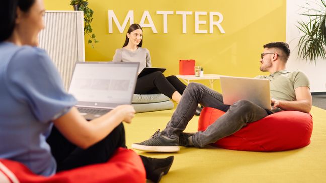 3 Mitarbeiter auf modernen Sitzsäcken im Loungebereich der IT sitzend. Alle haben einen Laptop auf den Knien.