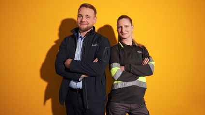 Logistikmitarbeiter 2er Gruppe vor gelbem Hintergrund mit Armen verschränkt