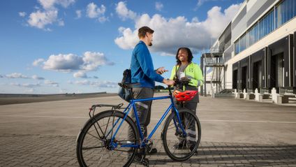 Mitarbeitende stehen vor dem Logistikzentrum mit einem Fahrrad