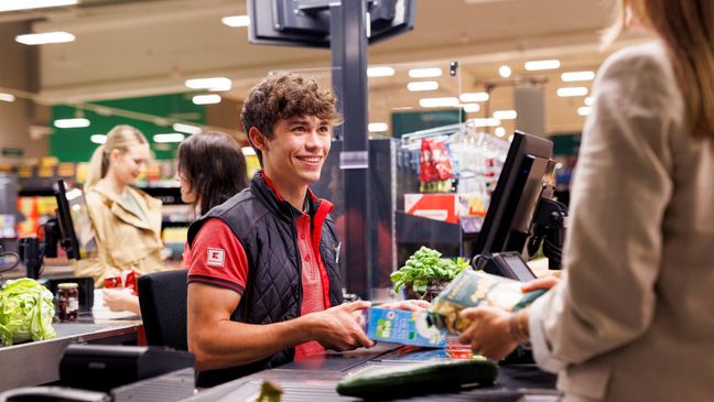 An der Kasse in einer Kaufland-Filiale: Junger Mitarbeiter kassiert den Einkauf einer Kundin.