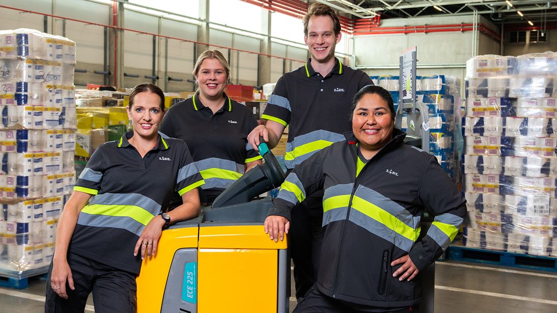 Groep Lidl-medewerkers poserend bij een elektrische pompwagen in het distributiecentrum