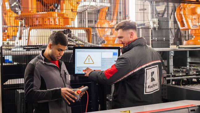 Zwei Mitarbeiter in der Logistik bei Kaufland arbeiten an einer Automatisierungsanlage.