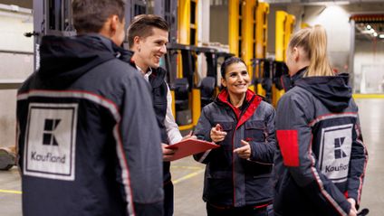 Vier Logistikmitarbeiter von Kaufland unterhalten sich in einer Verladehalle.