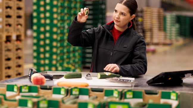 Eine Auszubildende zur Fachkraft für Lagerlogistik bei Kaufland prüft die Qualität von frischem Gemüse im Logistikzentrum.