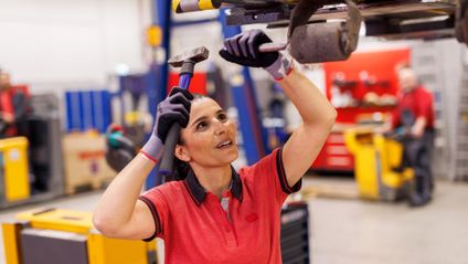 Logistikmitarbeiterin von Kaufland bei Wartungsarbeiten mit Hammer und Stecheisen.