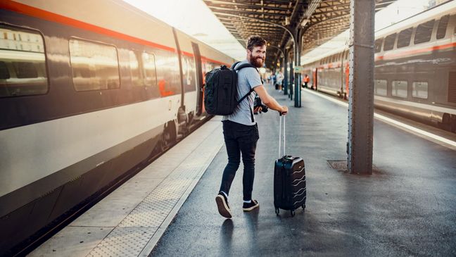 Mann steht an Bahnsteig und ist bereit für seine Reise.