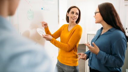 Mitarbeiterentwicklung: 2 Kaufland-Kolleginnen im Gespräch am Whiteboard.